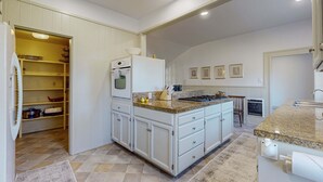Una cucina con mobili bianchi, un piano di lavoro in granito e un forno integrato.