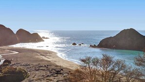 Un paisaje costero con formaciones rocosas, una playa arenosa y aguas azules cristalinas.