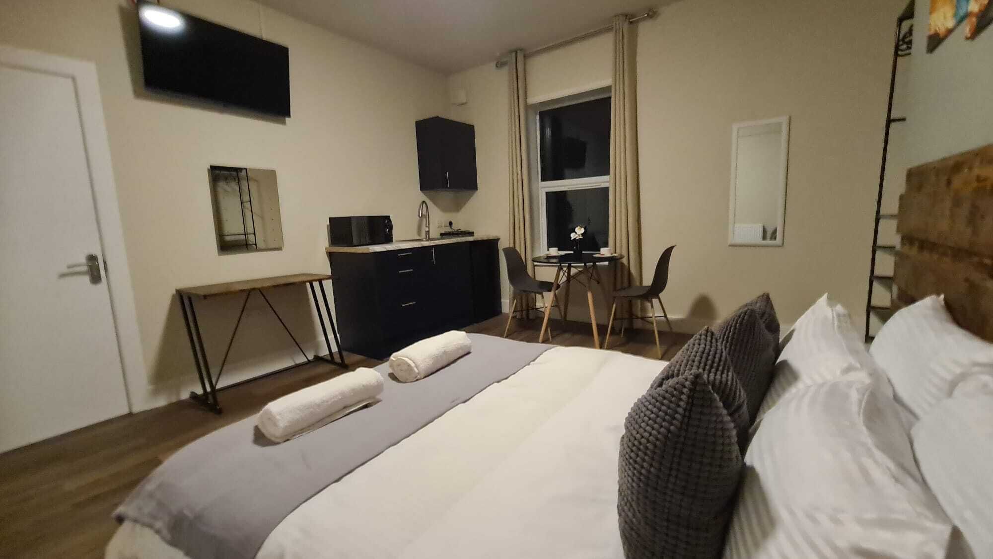 A hotel room with a bed, a desk, a chair, a TV, and a window.