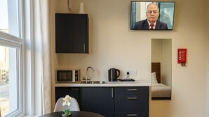 A modern hotel room with a dining area, a kitchen, and a TV mounted on the wall. - City Stays Norwich (Norwich)