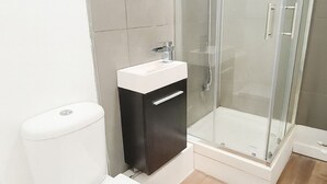 A modern bathroom with a toilet, a sink, and a glass-enclosed shower. - City Stays Norwich (Norwich)