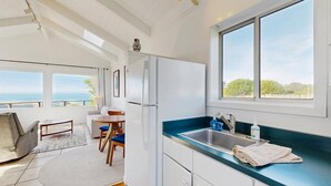 Una cocina moderna con un amplio ventanal, un comedor con mesa y sillas, y vista al mar.