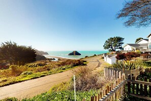 A coastal road with a wooden fence, a beach, and houses with ocean views. - Oceanview Studio - Beach, Fireplace & Deck (Elk)