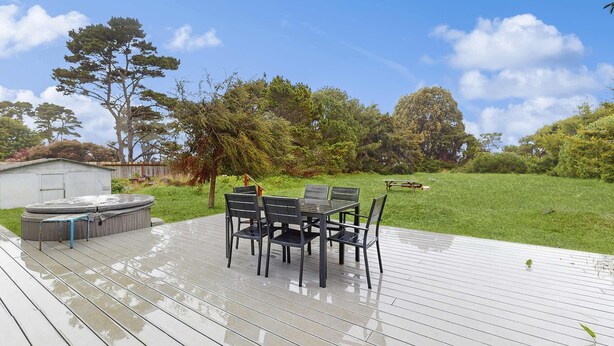 Una terraza de madera con jacuzzi y una mesa con sillas.