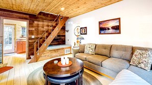 Un interior de madera con una escalera, un sofá y una mesa de comedor.