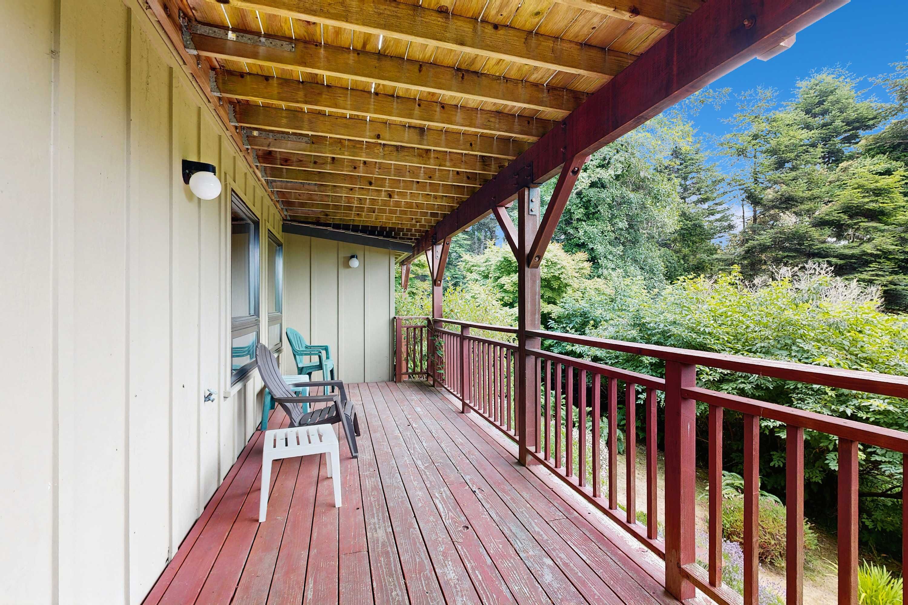 Une terrasse en bois avec une rambarde rouge, une chaise blanche et une table.