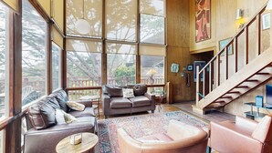 Un vaste espace de vie doté de grandes fenêtres, d’un escalier et d’un coin salon confortable.
