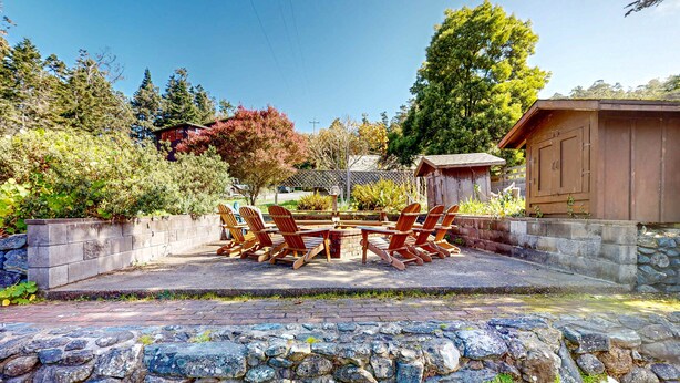 Eine Terrasse mit einer Steinmauer, einem Holztisch und Stühlen.