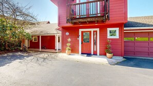 Ein zweistöckiges rotes Haus mit Balkon, Garage und Topfpflanzen.
