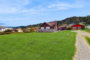 A rural setting with a grassy field, a wooden house, and a red barn.
