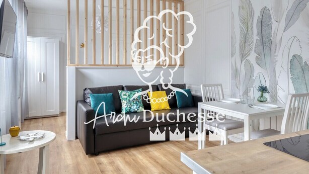 A modern living room with a sofa, a dining table, and a decorative wall. - Blue Bird, charmant studio avec place de parking ! (Rouen)
