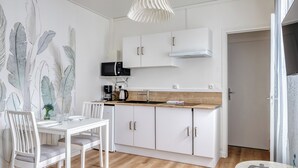 A modern kitchen with white cabinetry, a wooden countertop, and a built-in microwave. - Blue Bird, charmant studio avec place de parking ! (Rouen)