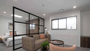 A modern hotel room with a large window, a sofa, a small table, and a bed. - Treat yourself - luxury inner-city apartment (Dunedin)