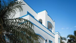 Un bâtiment moderne de couleur blanche, agrémenté de touches de bleu, se dressant sous un ciel d’un bleu limpide.