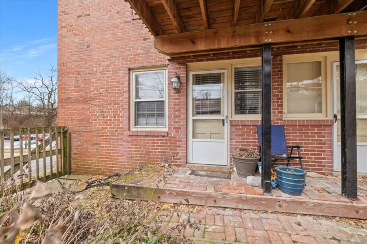 A brick building with a covered porch, a door, and windows.