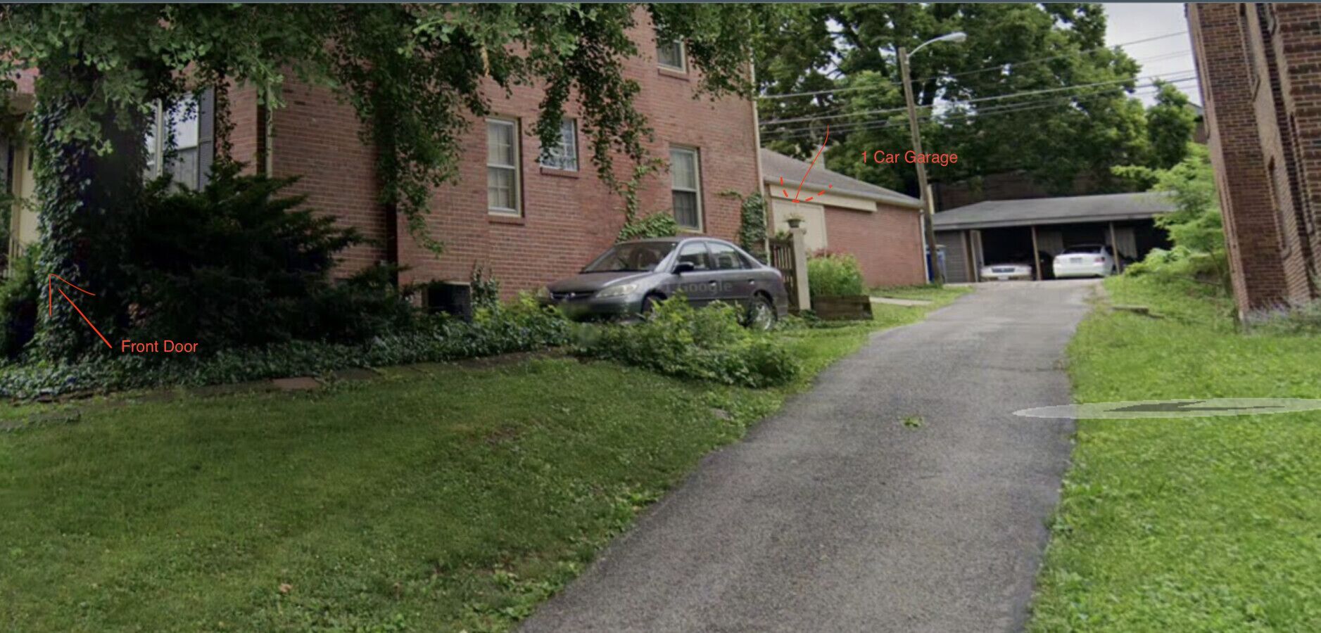 A residential driveway with a car parked on the side, a front door, and a garage.