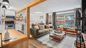 Una sala moderna con sofá, mesa de centro y área de cocina con electrodomésticos.