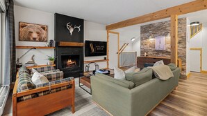 Una sala de estar moderna con chimenea, un sofá, una cama y una escalera que sube a un nivel superior.