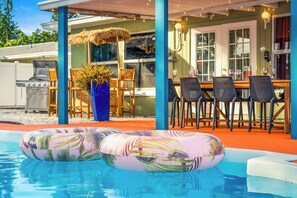 Ein Poolbereich mit Schwimmreifen, Grill und Gartenmöbeln.