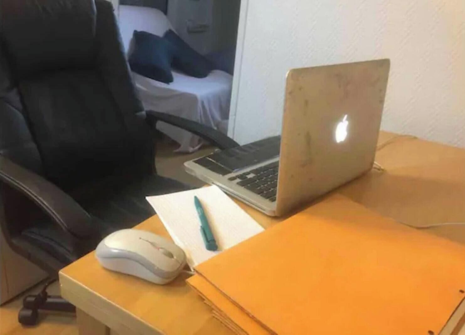 Una computadora portátil sobre un escritorio con un ratón, un bolígrafo y una carpeta.