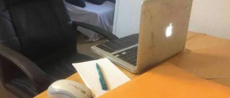 Una computadora portátil sobre un escritorio con un ratón, un bolígrafo y una carpeta.