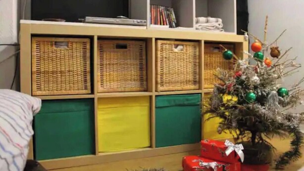 A room with a bookshelf, wicker baskets, a Christmas tree, and wrapped gifts. - Beau Studio Rue Didot (Paris)