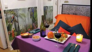 A dining table with a purple tablecloth, a bottle of wine, a plate of food, and a candle. - Beau Studio Rue Didot (Paris)