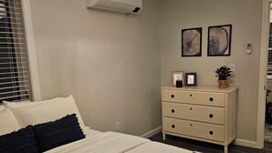 Une chambre à coucher avec un lit, une commode et deux tableaux accrochés au mur.