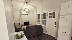 Un espace de vie compact comprenant un coin repas, un canapé, un téléviseur et un luminaire au plafond.