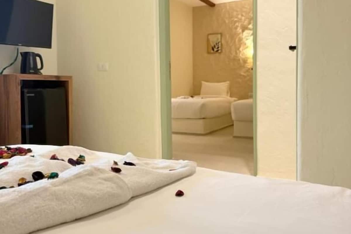 A bedroom with a bed, a TV, and a wooden cabinet.