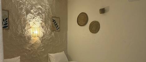 A room with two beds, a textured wall, a wall-mounted air conditioner, and two wall-mounted decorative items.
