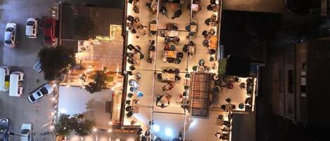 An aerial view of a hotel with multiple dining areas, outdoor seating, and a parking lot.