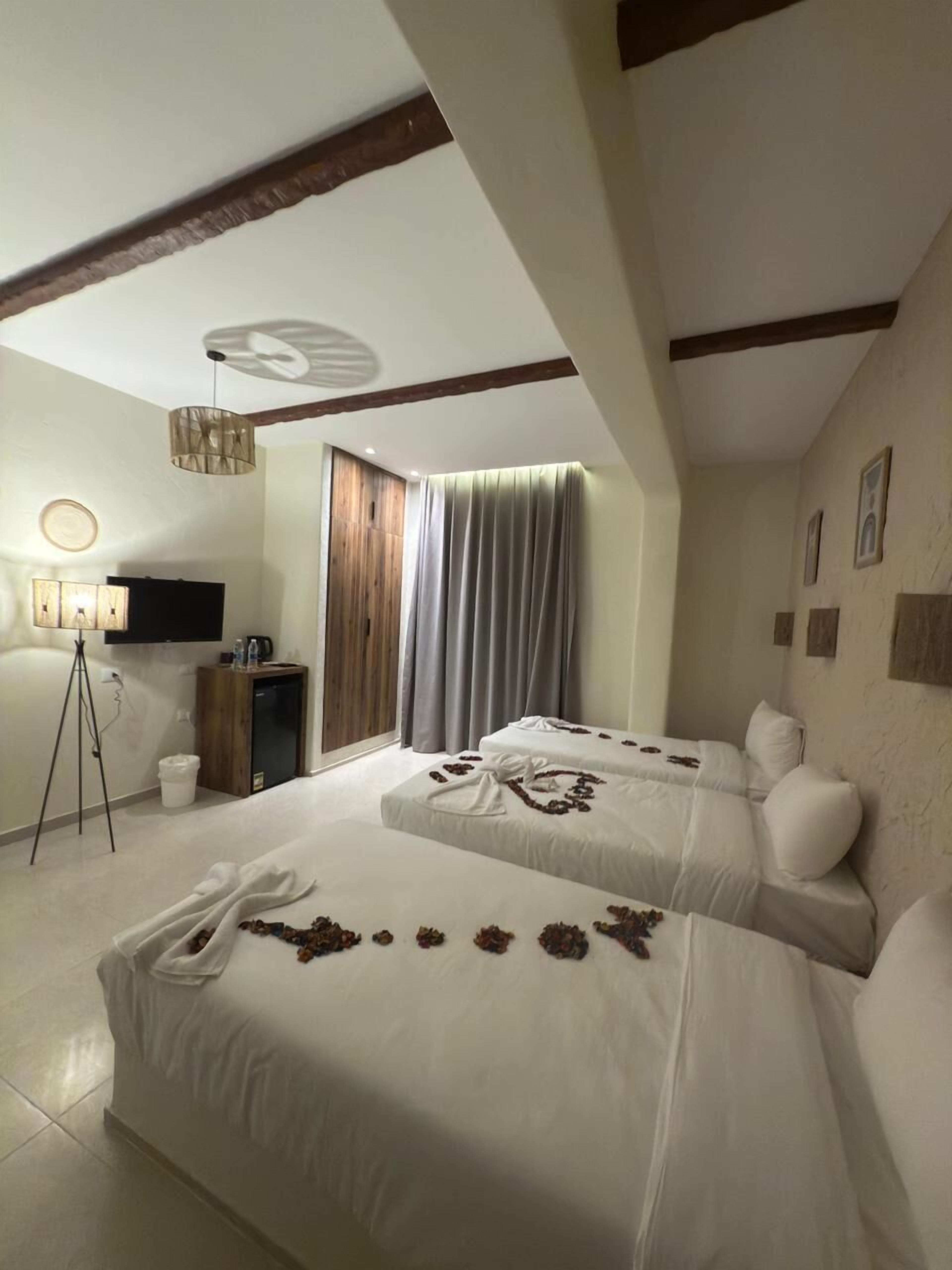 A hotel room with two beds, a TV, a desk, and a tripod.