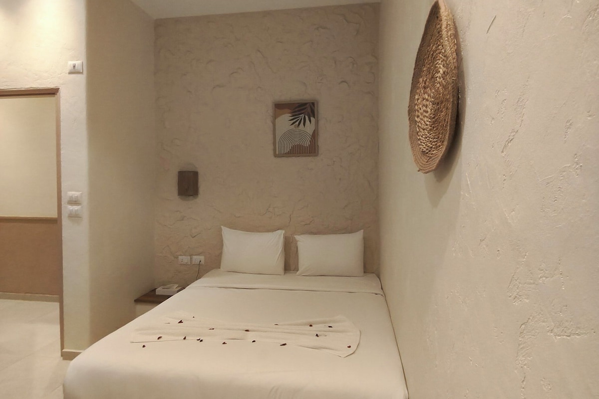 A bedroom with a bed, a wall-mounted air conditioner, a textured wall, and a small decorative item.