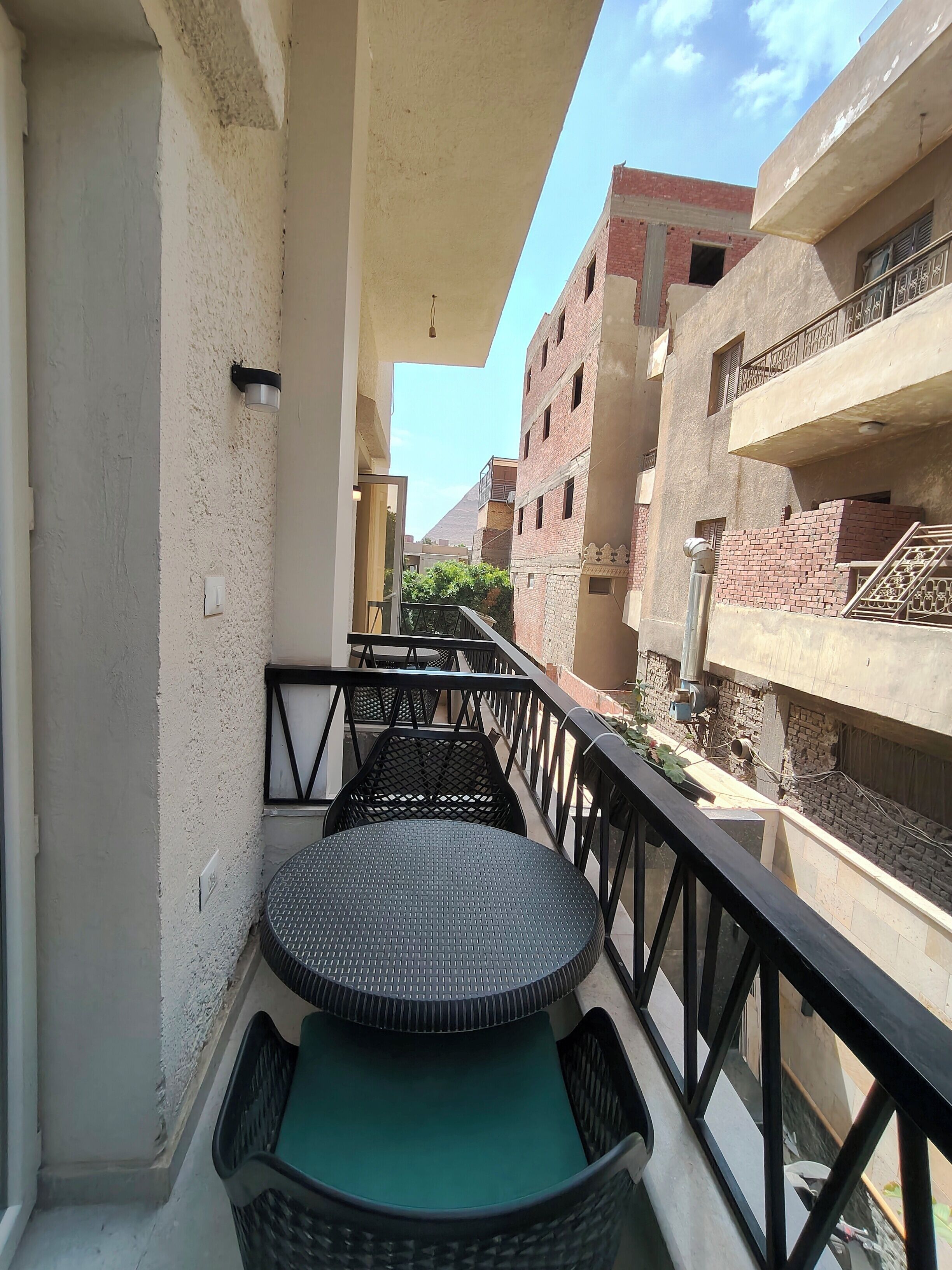 A balcony with a round table and chairs, a railing, and a view of adjacent buildings.