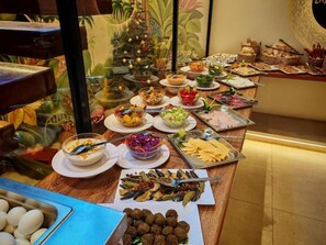 A buffet table with various dishes, a Christmas tree, and a tropical mural. - Pyramids Spiritual Gate (Giza)