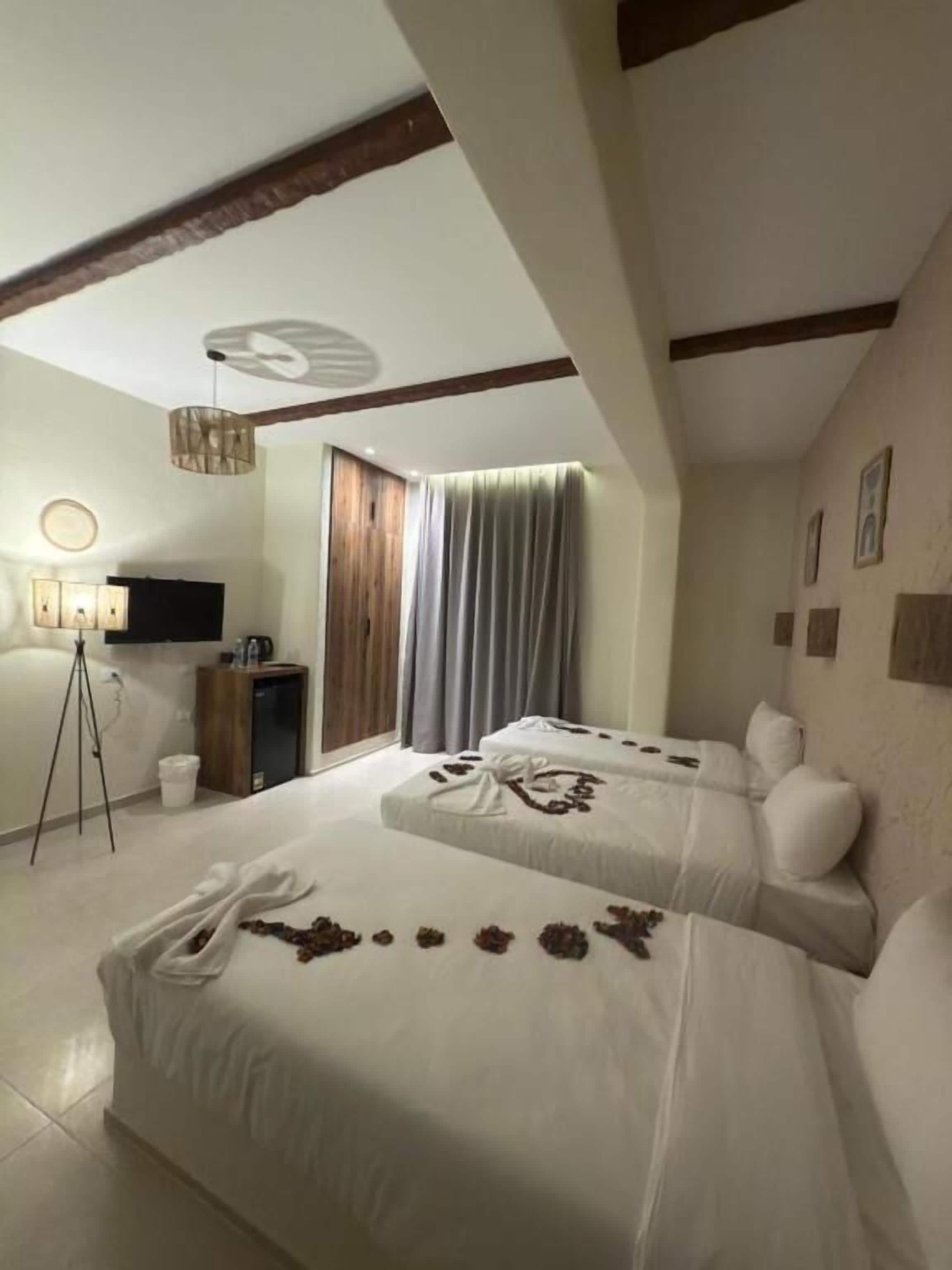 A hotel room with two beds, a television, a desk, and a tripod.