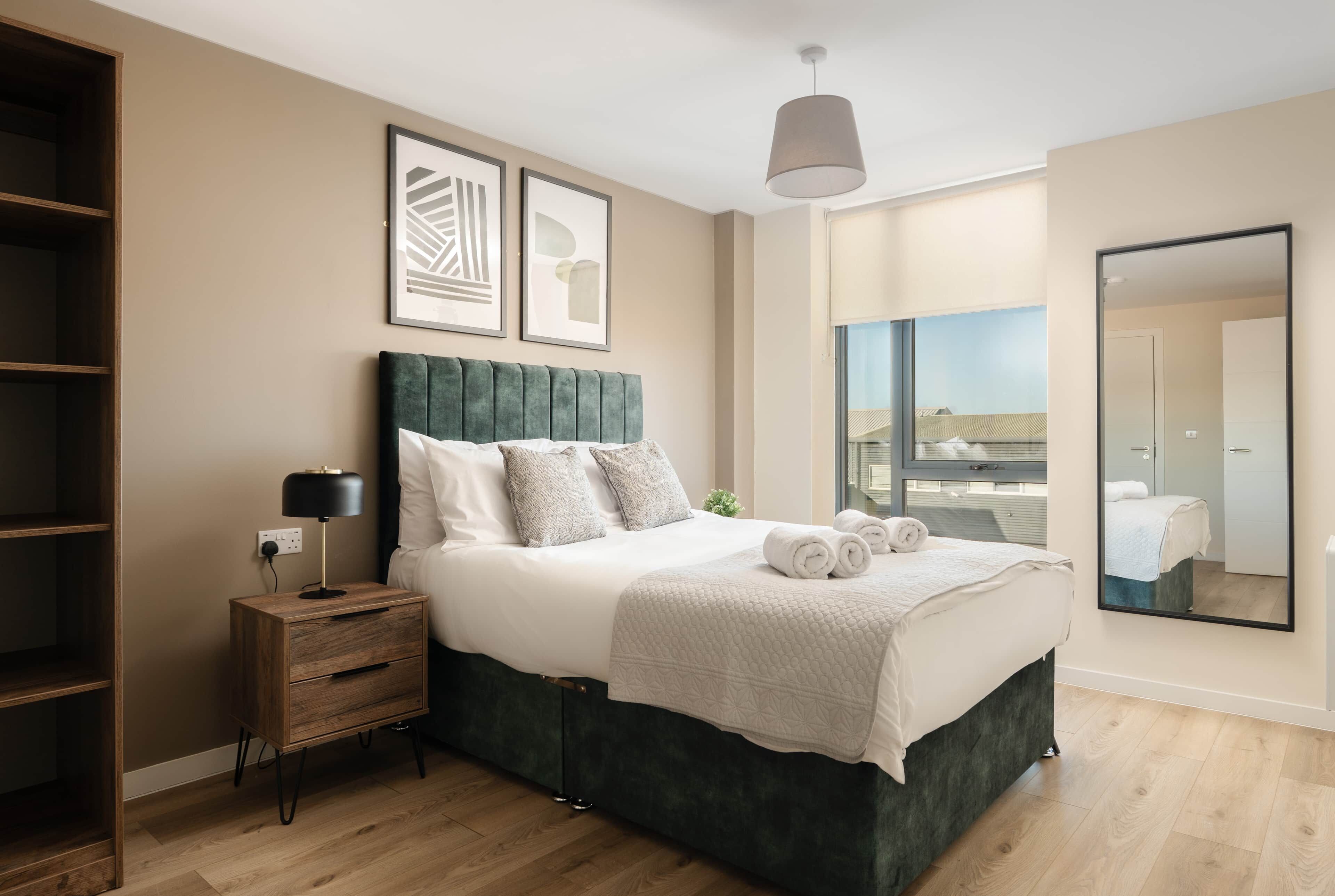 A modern bedroom with a large bed, bedside table, and a wardrobe.