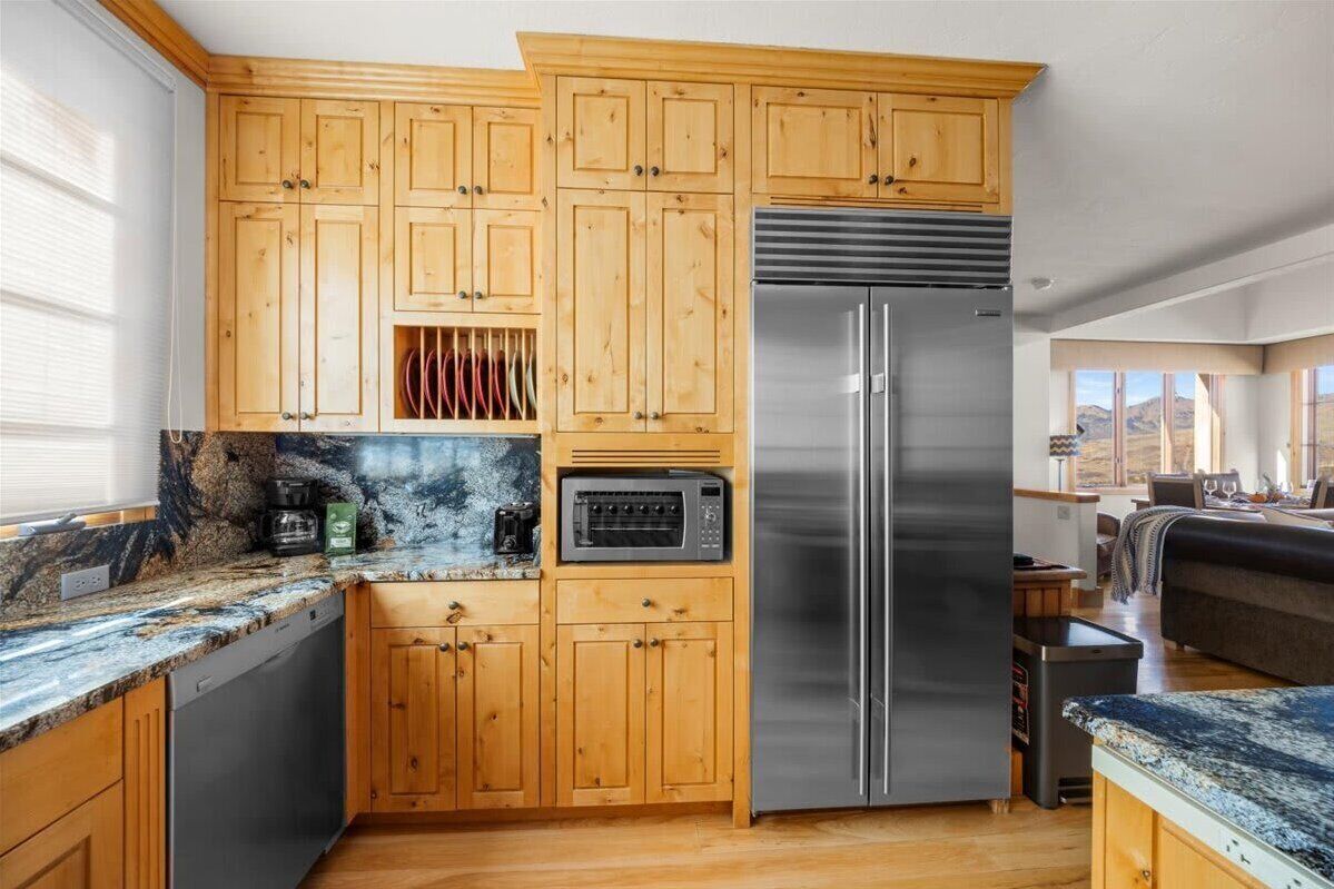 A kitchen with wooden cabinets, a stainless steel refrigerator, and a built-in microwave.