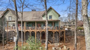 Ein zweistöckiges Holzhaus mit Balkon, umgeben von Bäumen.