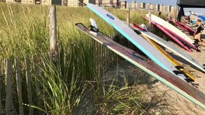 A row of canoes lined up on a sandy beach with tall grass in the foreground and buildings in the background. - Private Charming 2 bedroom steps from the beach
Entire rental unit in Queens, NY (Rockaway Beach)