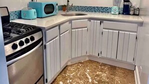 A kitchen with white cabinets, a stove, a microwave, and a sink. - Private Charming 2 bedroom steps from the beach
Entire rental unit in Queens, NY (Rockaway Beach)