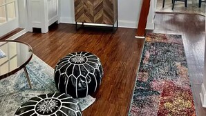 A modern living room with a herringbone-patterned cabinet, a large flat-screen TV, a potted plant, and a dining area with chairs. - Private Charming 2 bedroom steps from the beach
Entire rental unit in Queens, NY (Rockaway Beach)