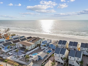 A coastal residential area with houses, a swimming pool, and a beach. - Beachfront condo with stunning Gulf views, pool access, and modern comforts. (Indian Shores)