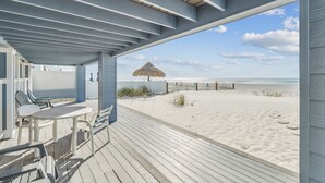 Un espace extérieur abrité, doté d’une terrasse en bois, de sièges et offrant une vue sur la plage.
