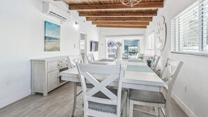 Un espace repas doté d’un plafond en bois, de murs blancs et offrant une vue sur l’extérieur.
