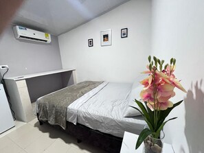 A small, neatly arranged bedroom with a bed, a desk, and a potted plant. - CASAMARTINA (Cartagena)