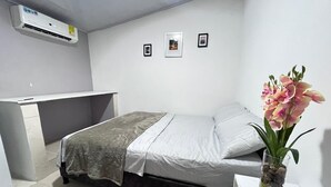 A bedroom with a bed, a desk, and a vase with flowers. - CASAMARTINA (Cartagena)