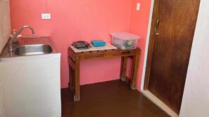 A small kitchen with a sink, a wooden table, and a pink wall. - CASAMARTINA (Cartagena)
