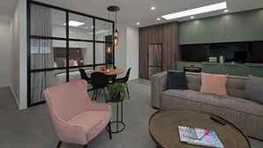 Un salon moderne comprenant un canapé, un fauteuil, une table basse et un coin repas avec des chaises et une table.